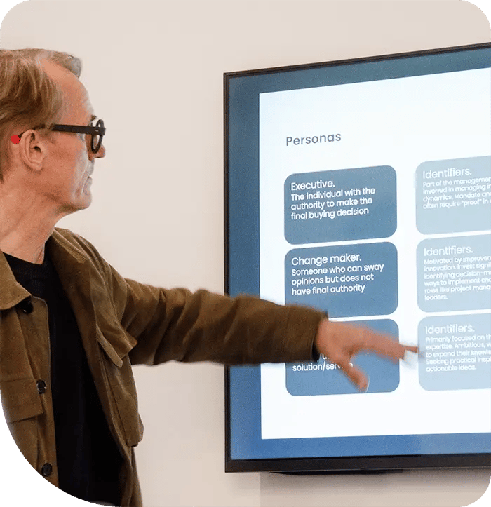 A person points at a screen showing a “Personas” presentation slide