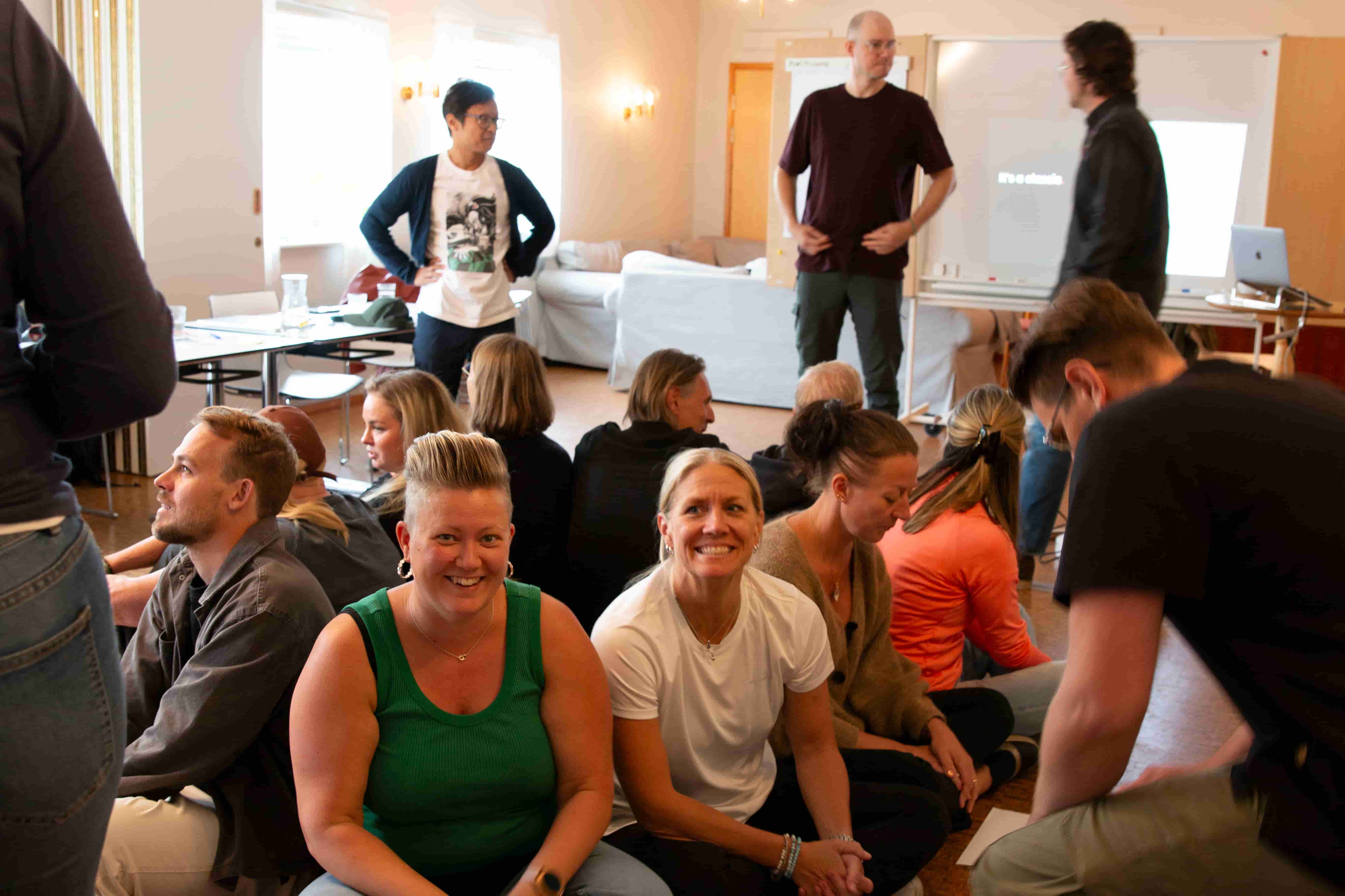 Team members gathered indoors during a workshop session, smiling and engaging in group activities at the Zooma kick-off.