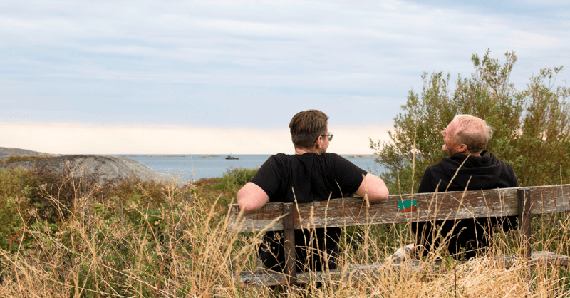Two colleagues sitting on a wooden bench overlooking the sea on Vrångö island, Sweden